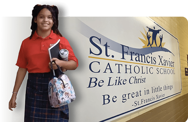 Student in front of St. Francis Xavier Catholic School sign